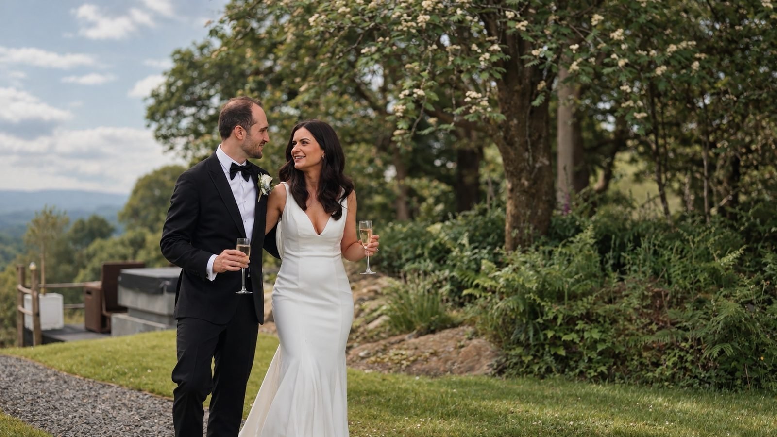 Couple in black tie walking with champagne above a valley